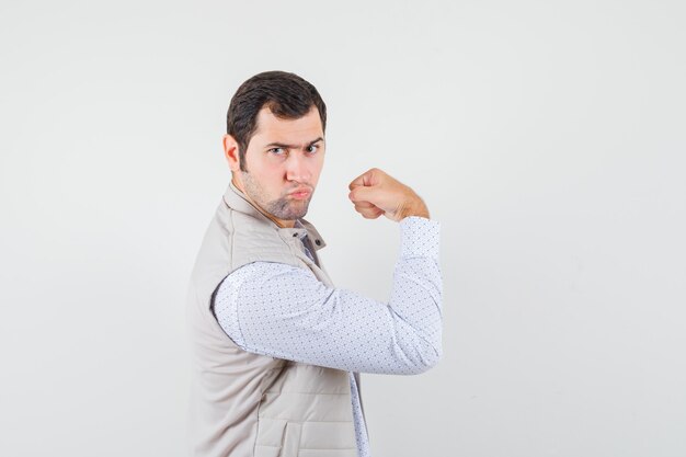 Young male showing muscles of arm in shirt