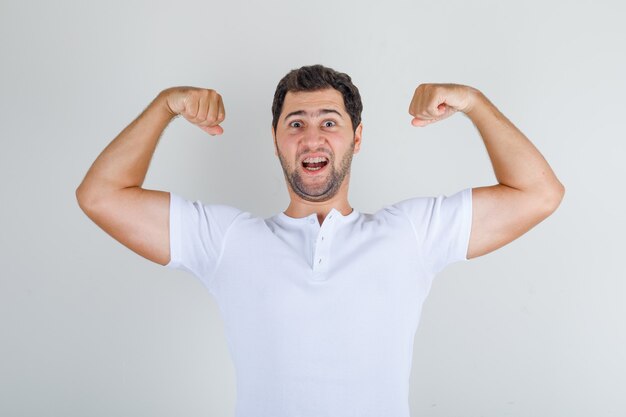 Young male showing muscles in white t-shirt and looking energetic