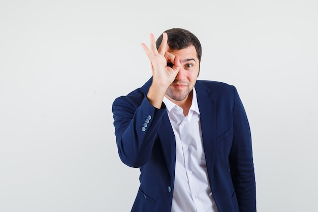 Young male showing ok gesture in shirt and jacket and looking confident