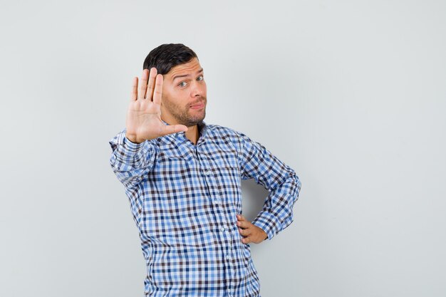 Young male showing refusal gesture in checked shirt and looking decisive