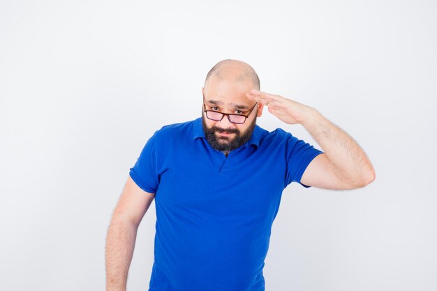 Young male showing soldier greeting in blue shirt,glasses , front view.