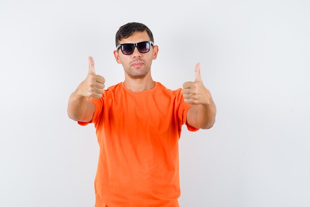 オレンジ色のTシャツに親指を立ててクールに見える若い男性