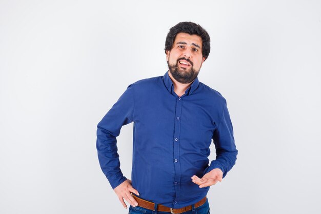 Young male speaking in royal blue shirt and looking talkative , front view.