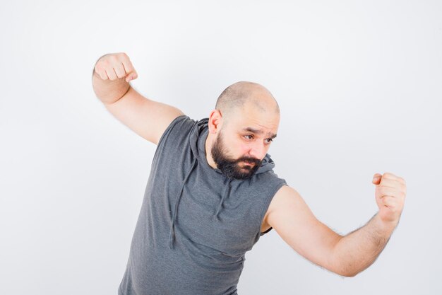 Young male standing in fight pose in sleeveless hoodie and looking confident. front view.