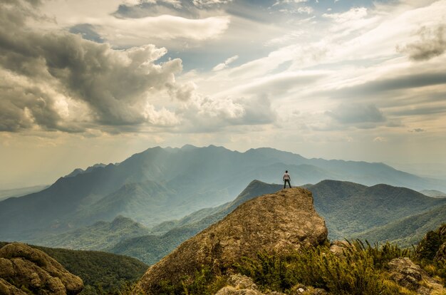 Young male standing on top of the hill under a cloudy blue sky