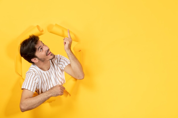 Foto gratuita giovane maschio che sta sul ragazzo di vendita dell'interno del fondo di carta giallo strappato