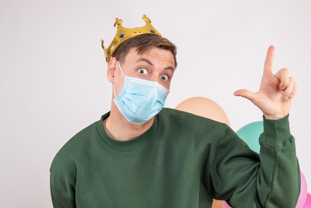 young male in sterile mask holding colorful balloons on white