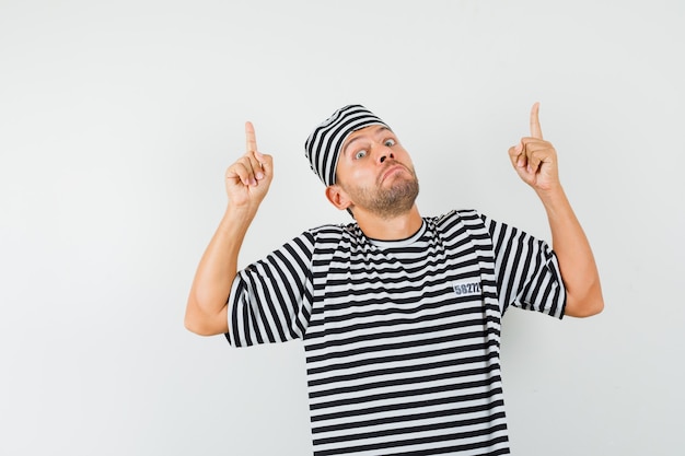 Young male in striped t-shirt hat pointing up and looking puzzled  