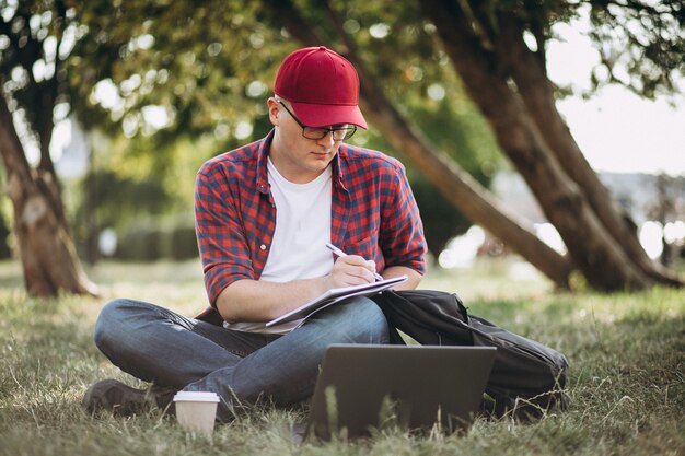 Young male student working on a computer in park