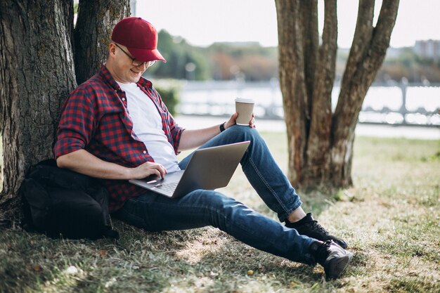 公園内のコンピューターに取り組んでいる若い男性学生