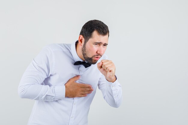 Young male suffering from cough in white shirt and looking ill. front view.