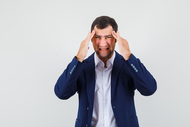 Young male suffering from headache in shirt, jacket and looking tired