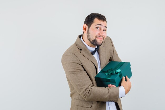 スーツを着た若い男性がプレゼントボックスを持って、嬉しそうに見える、正面図。