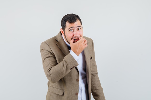 Young male in suit whistling with fingers , front view.