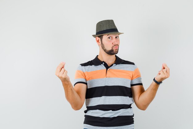 Tシャツを着た若い男性、手と指で身振りで示す帽子、自信を持って見える、正面図。