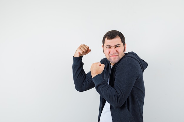 Free photo young male in t-shirt, jacket showing winner gesture and looking lucky, front view.