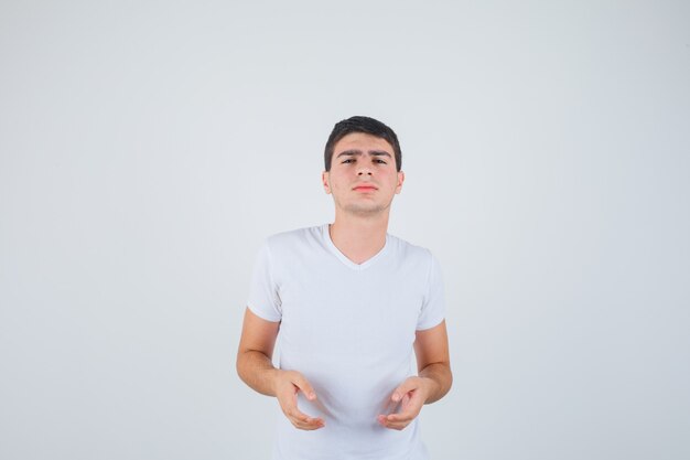 Young male in t-shirt posing while looking at camera and looking serious , front view.