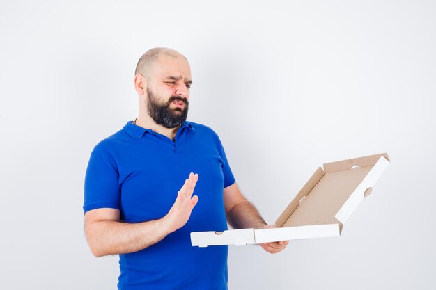 Young male in t-shirt showing refusal gesture and looking confused , front view.