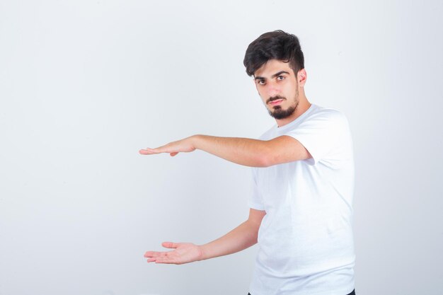 Young male in t-shirt showing size sign and looking confident , front view.