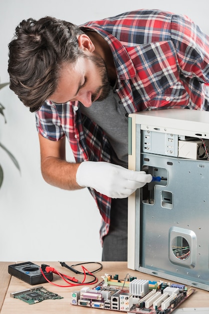 Free photo young male technician examining computer in workshop