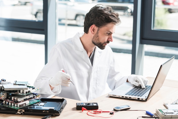 Foto gratuita giovane tecnico maschio che utilizza computer portatile nell'officina