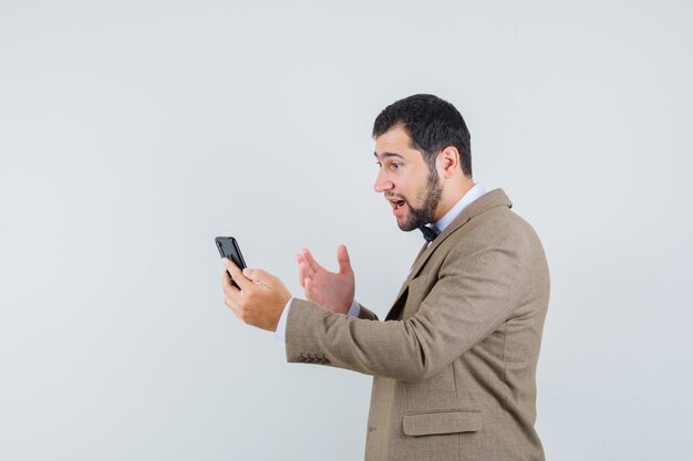 Young male trying to explain something on video chat in suit .