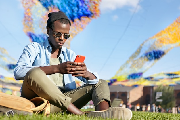 young male wearing stylish clothes while sitting at green grass