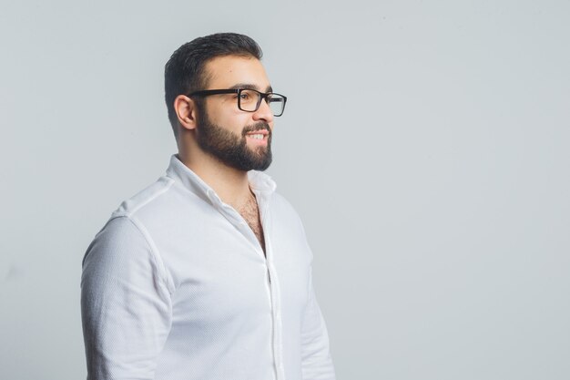 Young male in white shirt looking away while smiling and looking elegant .