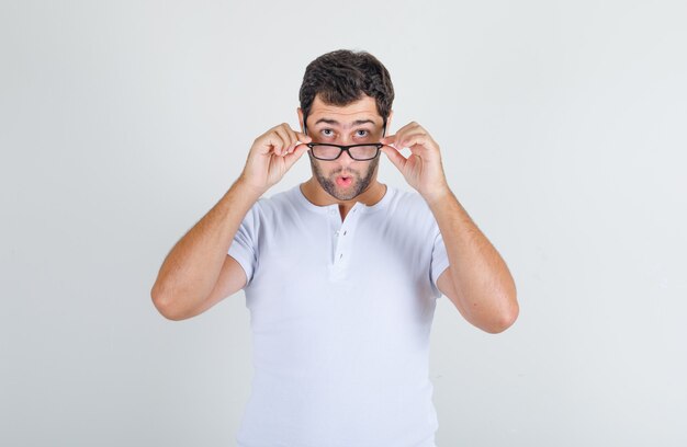 Young male in white t-shirt looking over glasses