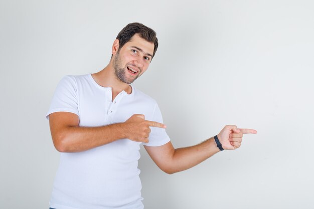 Young male in white t-shirt pointing fingers away and looking energetic
