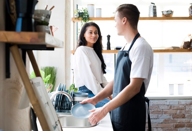 Young male with apron looking at ethnic girlfriend