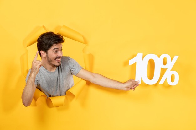 Young male with inscription sign on torn yellow paper background facial guy sale