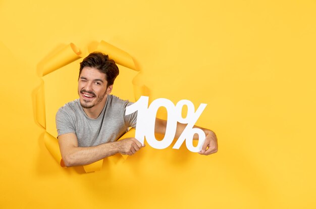 Young male with inscription sign on torn yellow paper background guy facial indoor