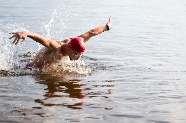 Young male with red cap swimming in lake