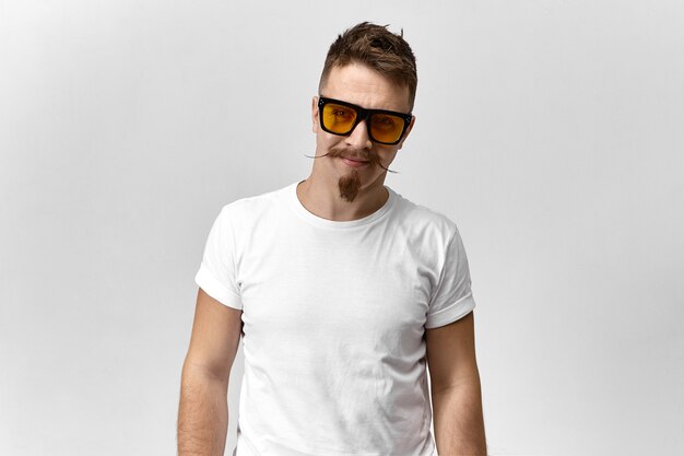 Free photo young male with stylish beard and moustache smiling wearing yellow eyeglasses