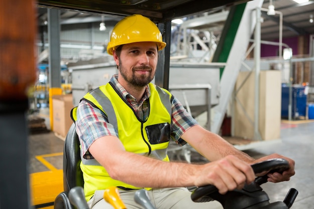 Young male worker driving forklift in warehouse