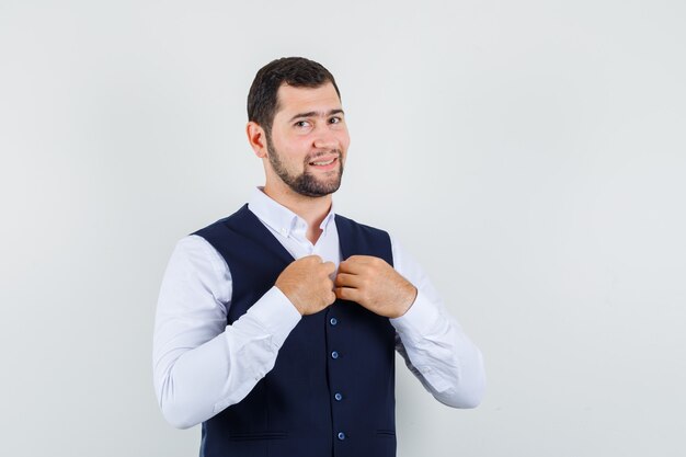 Young man adjusting collar of vest in suit and looking nice