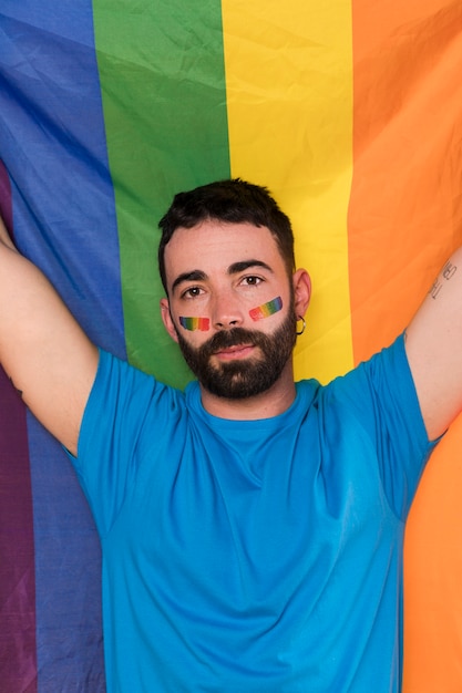 Foto gratuita giovane uomo contro la bandiera arcobaleno