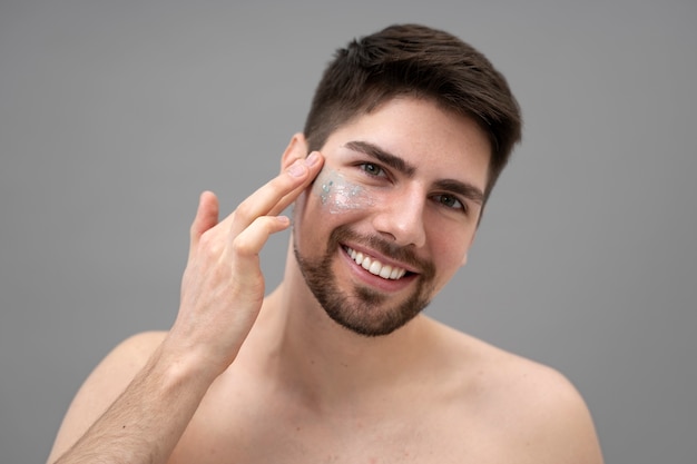 Young man applying shiny lotion on her face