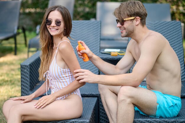 Young man applying spf cream on his womans body