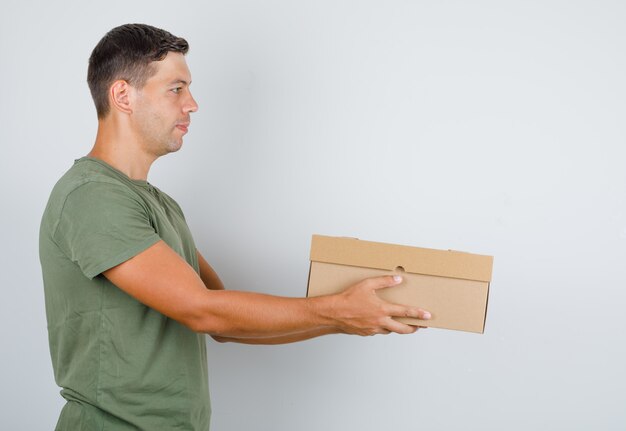 Young man in army green t-shirt delivering cardboard box .