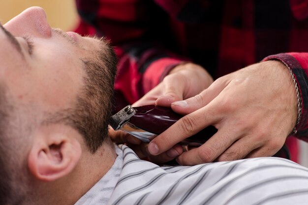 Young man arranging his beard with a shaving machine