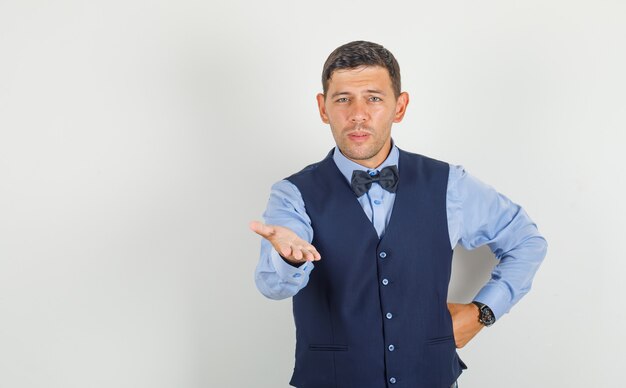 Young man asking question with hand on waist in suit