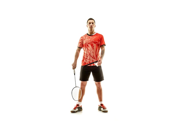 Young man badminton player standing over white studio wall