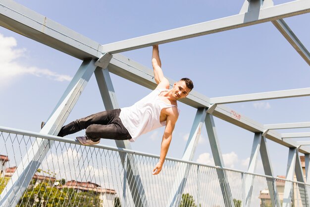 Young man balancing on the railing of a bridge