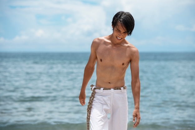 Foto gratuita giovane sulla spiaggia che si prepara a praticare la capoeira