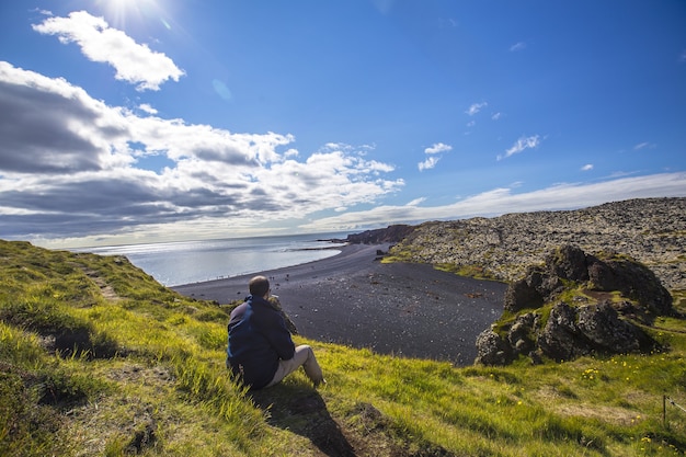 자연적인 관점에서 Snaefellsnes 반도의 아름다운 돌 해변에 젊은 남자