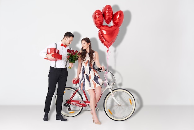 Young man bestowing woman by gift and roses