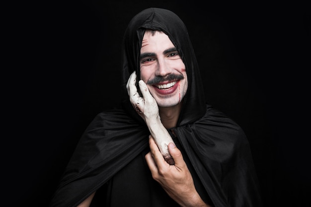 Free photo young man in black clothes holding corpse hand and smiling