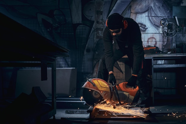 Free photo young man in black gloves polishing metal in dark room